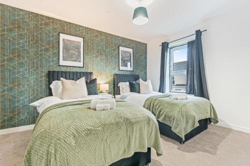 two beds in a room with green wallpaper at Spacious 4-Bed Home Near Cribbs & Bristol in Bristol
