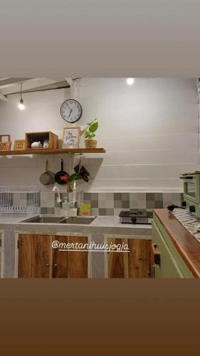 a kitchen with a sink and a clock on the wall at Mertanihuisjogja in Salakan
