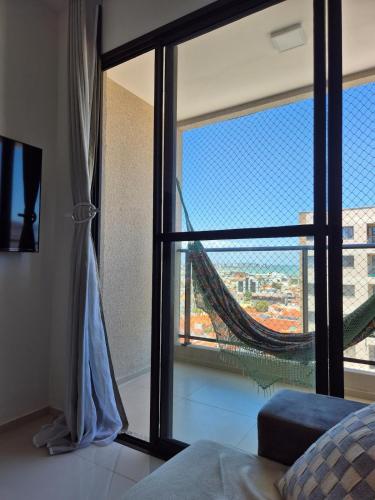 a room with a large window with a hammock outside at Beira Mar Apartment Aracaju in Aracaju