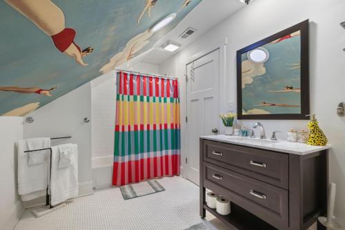 a bathroom with a colorful shower curtain and a sink at Stay & Play Indy- Indoor Fun - 5 Min to Downtown - Sleeps 10 - Arcade fun in Indianapolis