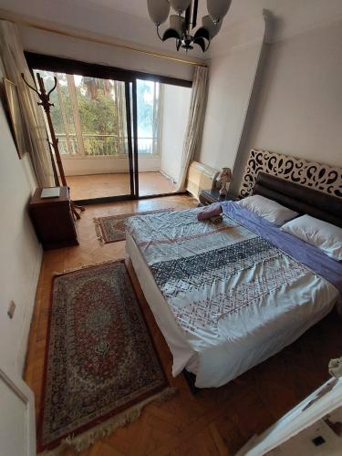 a bedroom with a large bed and a large window at Cozy Queen bed room in zamalek with garden view and balcony in Cairo