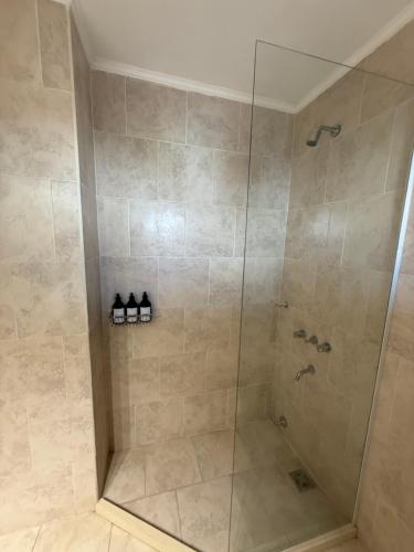 a shower with a glass door and some shoes at Studio Ikuma in Esperanza