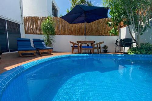 a swimming pool with two chairs and a table and an umbrella at Villa Sofia Boutique Hotel Cancun in Cancún