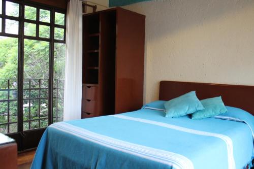 a bedroom with a bed with two blue pillows on it at Suites Calle Berlin in Mexico City