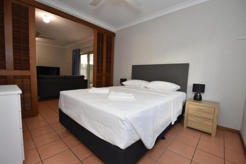 a bedroom with a large white bed and a couch at Royal Palm Villas in Cairns