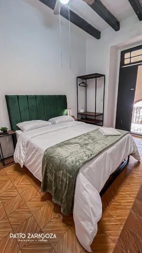 a bedroom with a large bed with a green headboard at Hotel PATIO ZARAGOZA, Centro Histórico SLP in San Luis Potosí