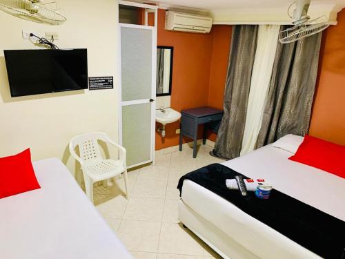 a hotel room with two beds and a television at Hotel Viajero Del Mar in Turbo
