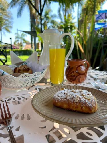 un tavolo con un piatto di cibo e un bicchiere di succo d'arancia di Posada Los Alcatraces ad Atlixco