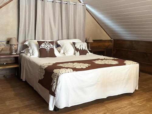 a bedroom with a large bed with white and brown sheets at Moana Waterfront Bungalow in Punaauia