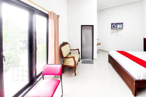 a bedroom with a bed and a chair and a window at RedDoorz Plus Syariah at Umyas Hotel near Terminal Anjuk Ladang Nganjuk in Nganjuk