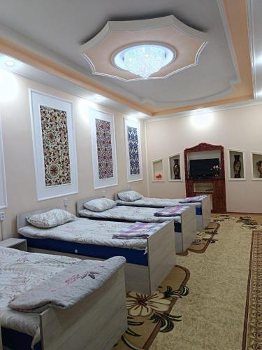 a room with four beds and a ceiling at Orzu Guest House in Bukhara