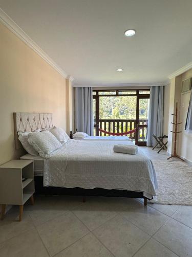 a bedroom with a large bed and a balcony at Ecopousada Garten Haus in Santa Teresa