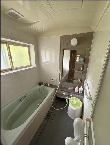 a bathroom with a tub and a sink and a mirror at 世界遺産平泉の一軒家ステイ 国際シェアハウス in Hiraizumi
