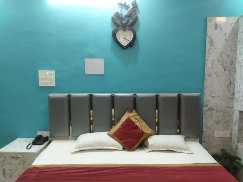 a blue wall with a clock above a bed at Hotel Evergreen in Arāria
