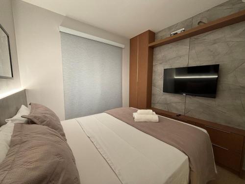 a bedroom with a bed and a flat screen tv at Apart Blend Marista Ar, Cozinha Próx ao Órion in Goiânia
