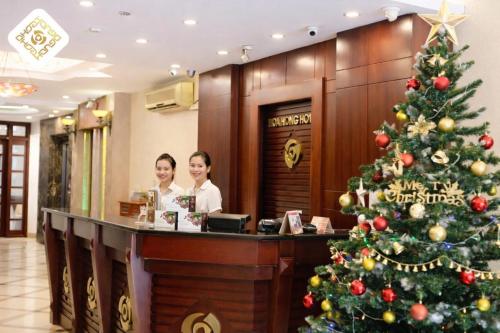 a christmas tree in a hotel lobby with two women at a counter at Hoa Hồng Hotel 2 - Xã Đàn in Hanoi