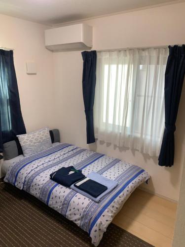 a bedroom with a bed with a blue and white comforter at Bessalov Home 1st room friendly house in Tokyo