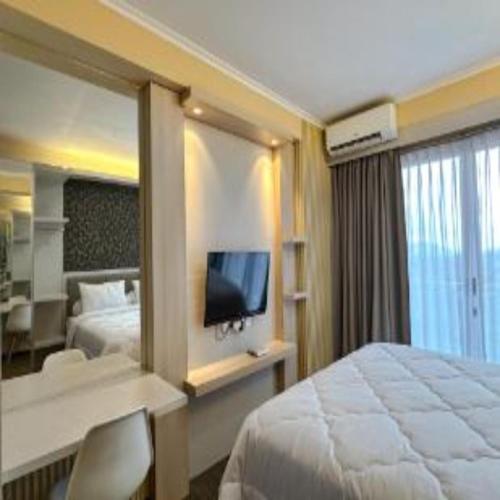 a hotel room with a large bed and a television at Delf Apartement Cpi Mewah By Selfiyani in Makassar