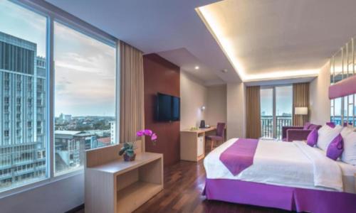 a hotel room with a large bed and a large window at Quest Hotel Darmo - Surabaya by ASTON in Surabaya