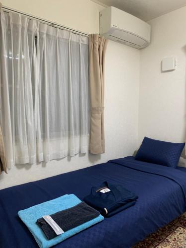 a bedroom with a blue bed with a towel on it at Bessalov Home 2nd room friendly house in Tokyo