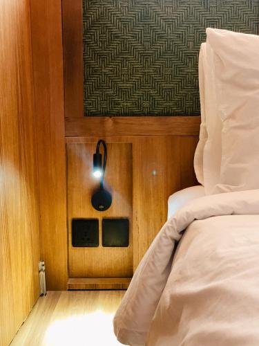 a room with a bed and a light on the wall at Leafy Riverbank in Tabanan