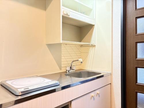 a small kitchen with a sink and a door at パルム天神西 in Susakiuramachi