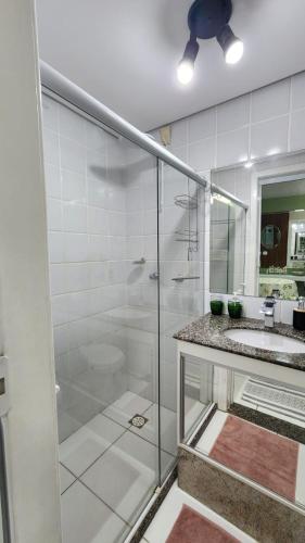 a bathroom with a glass shower and a sink at Studio Costa a Mar in Guarapari