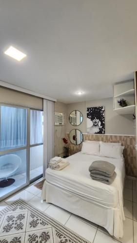 a white bedroom with a large bed and a bathroom at Studio Costa a Mar in Guarapari