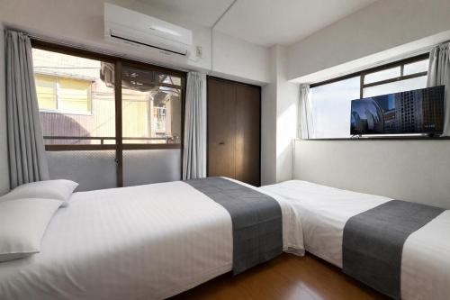 a bedroom with two beds and a window with a tv at パルム天神西 in Susakiuramachi