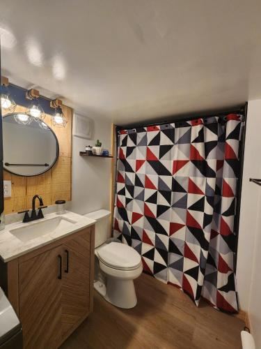 a bathroom with a toilet and a checkered shower curtain at Serenity Cabin - Cozy Mountain retreat near Shenandoah National Park in Luray