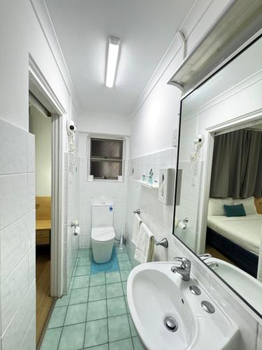 a bathroom with a sink and a toilet and a bed at Taree Motor Inn in Taree