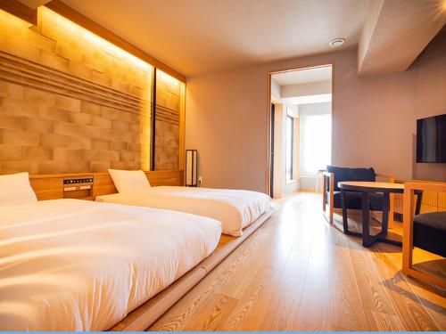 a bedroom with two beds and a desk and a tv at Yunokawa Prince Hotel Nagisatei in Hakodate