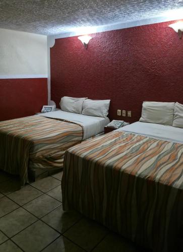 a hotel room with two beds and a red wall at El Pino - Hotel Economico Guadalajara in Guadalajara