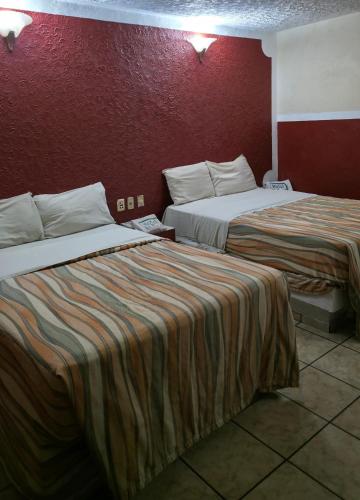 a hotel room with two beds and a red wall at El Pino - Hotel Economico Guadalajara in Guadalajara