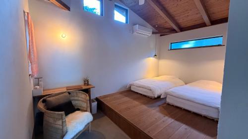 a bedroom with two beds and a chair in it at 月みるいえ in Akaoki