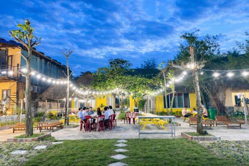 a group of people sitting at tables in a courtyard with lights at Newlife Homestay & Restaurant in Dong Hoi