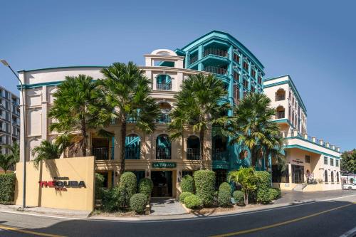 a building with palm trees in front of a street at The Quba Boutique Hotel Pattaya in Pattaya
