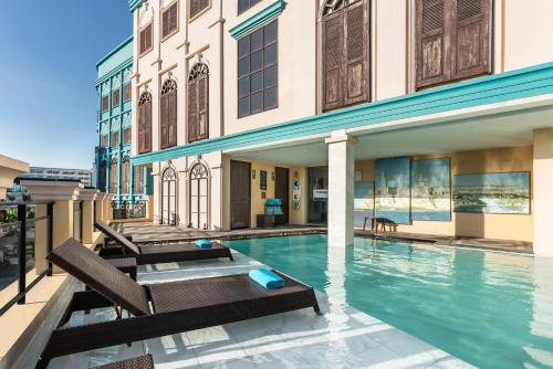 a swimming pool with two chairs and a building at The Quba Boutique Hotel Pattaya in Pattaya