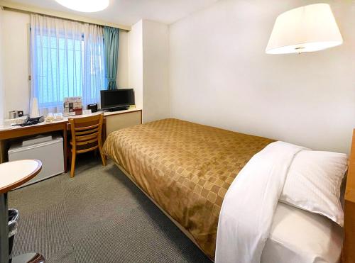 a hotel room with a bed and a desk with a computer at Hotel Trend Funabashi in Funabashi
