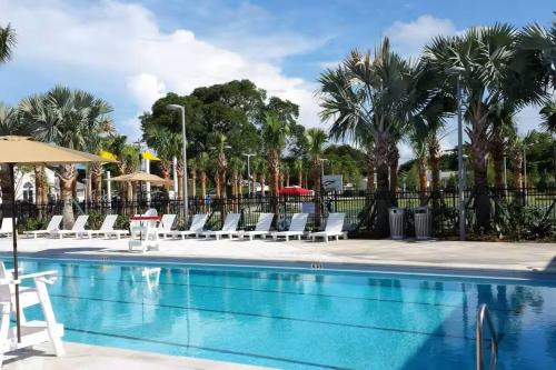 a pool with chairs and umbrellas and palm trees at Prime 2BR Location Near Miami FIFA World Cup Stadium - Private Parking - EV Station in Hallandale Beach