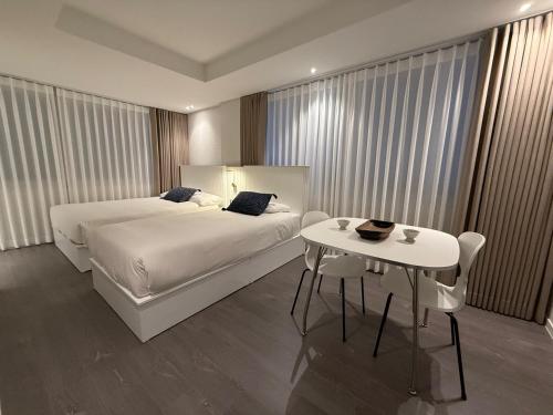 a hotel room with two beds and a table at DADA Stay Hongdae in Seoul