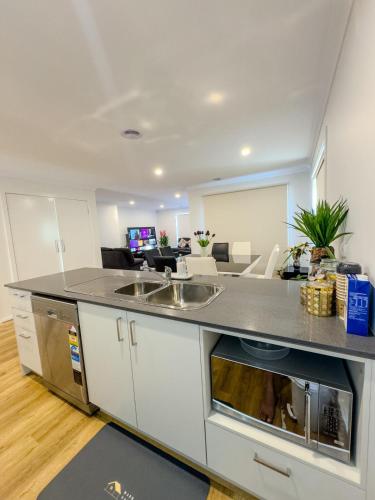 a kitchen with a sink and a living room at 3-Bedroom Modern Home in Clyde North in Clyde North