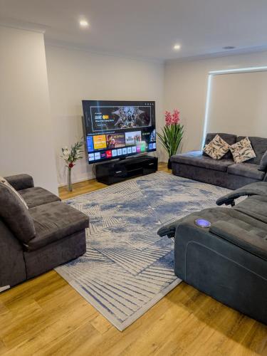 a living room with two couches and a flat screen tv at 3-Bedroom Modern Home in Clyde North in Clyde North