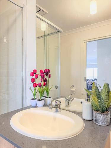 a bathroom with a sink and red tulips at 3-Bedroom Modern Home in Clyde North in Clyde North