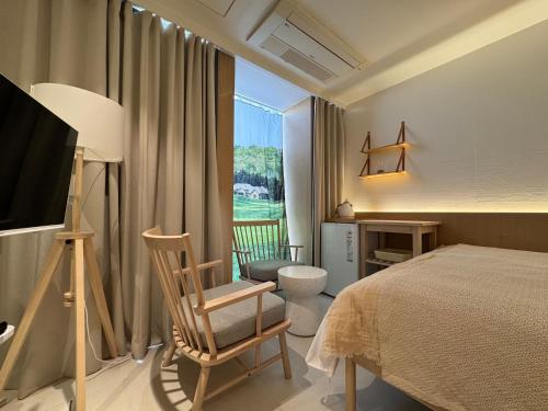 a bedroom with a bed and a chair and a window at 제주 디스피어 호텔 D-Sphere in Jeju