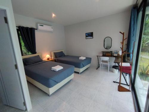 a bedroom with two beds and a table and a desk at Samui Land Haven in Taling Ngam Beach