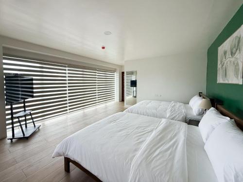 a bedroom with two beds and a green wall at The Nest Bed and Breakfast - Kalibo in Kalibo