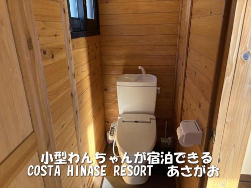a small bathroom with a toilet in a wooden room at Costa Hinase Resort in Kakui-jima