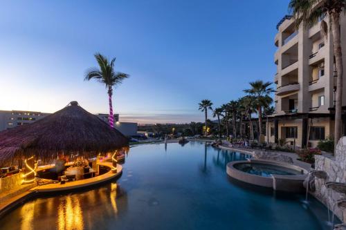 a pool at a resort with a restaurant and palm trees at Stunning 2 BR with Ocean Views & Jacuzzi by the Beach in Cabo San Lucas