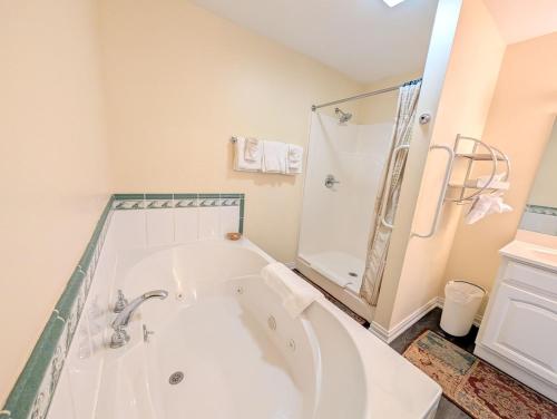 a white bathroom with a tub and a shower at The Falls Motel - 2 Mi to " Watkins Glen State Park, Wineries " and 4 Mi to Watkins Glen International Track " The Glen " in Watkins Glen